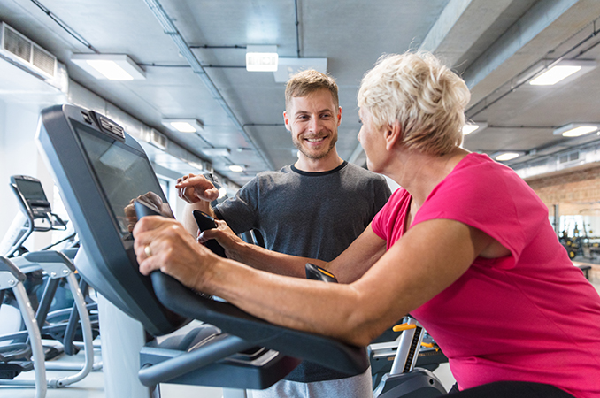 Seniorinainen kuntosalilla yhdessä personal trainerin kanssa.