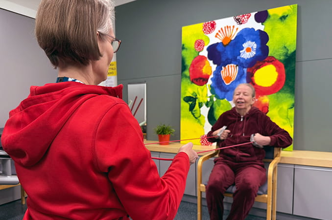 Fysioterapeutti jumppauttaa iäkästä naista.